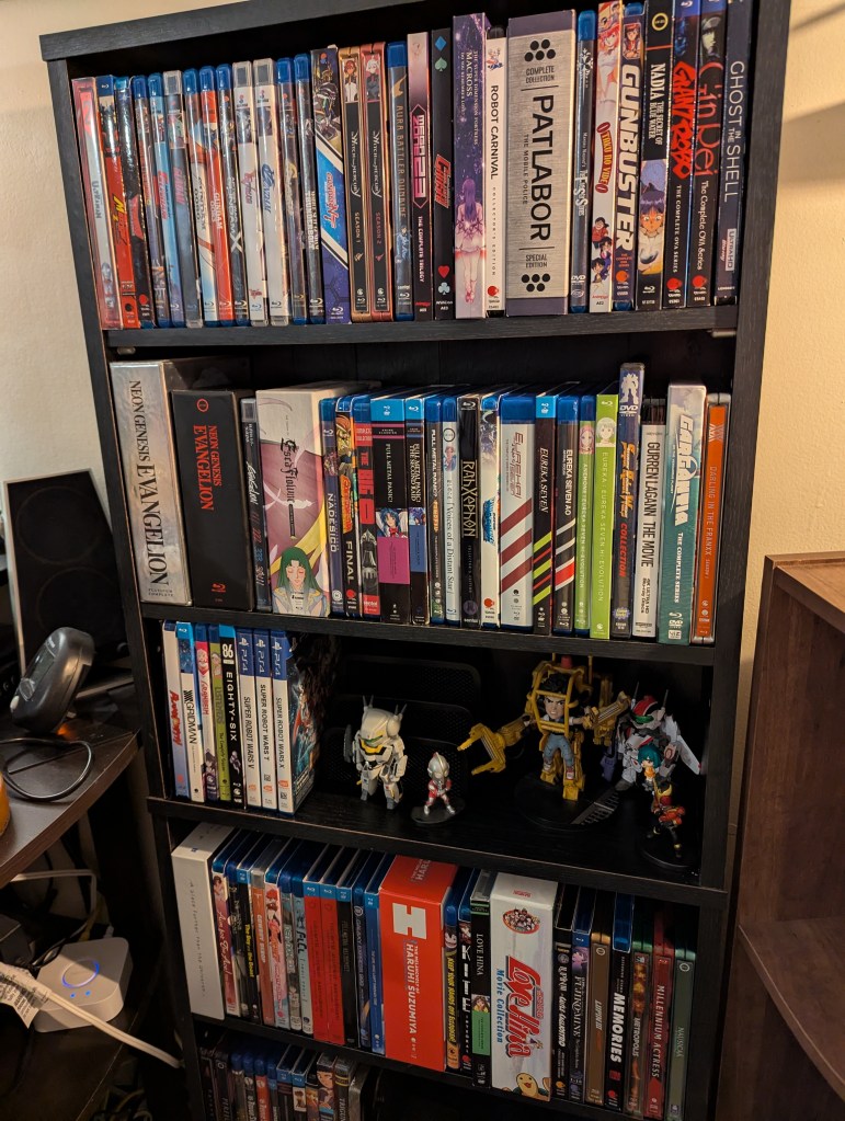A shelf filled with anime discs. One shelf has some empty space decorated with figurines.